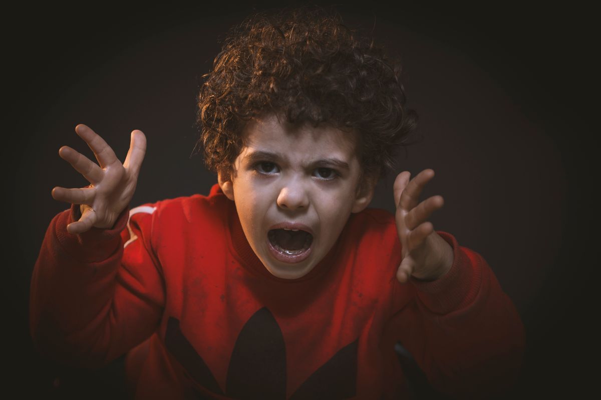 Child expressing intense anger with raised hands, in a moment of emotional dysregulation