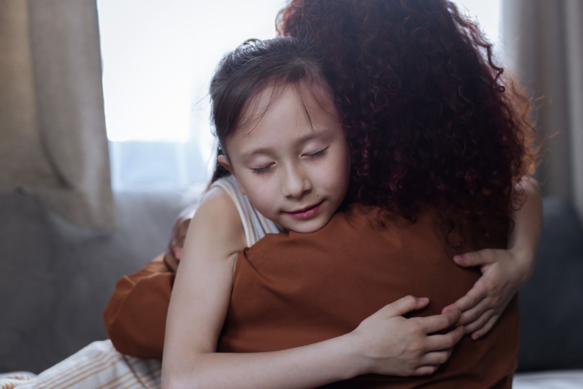 Parent comforting a child with a reassuring hug at home