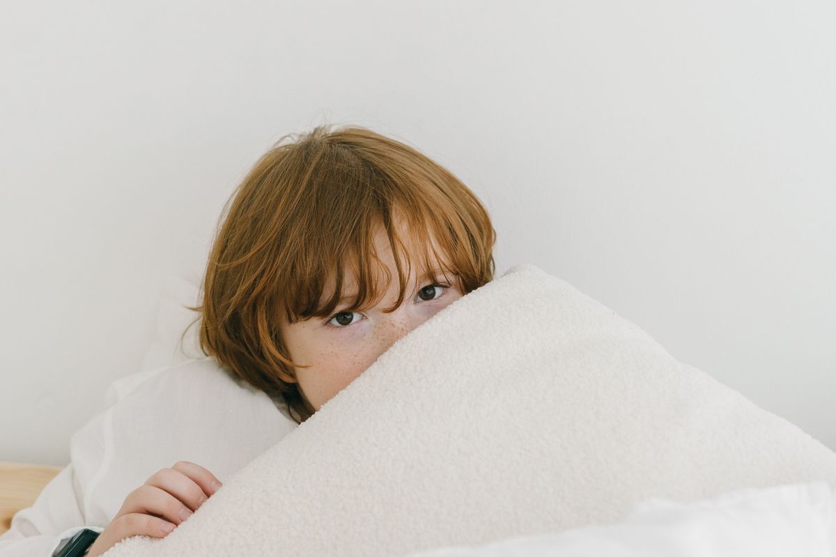 Silent child peeking over a blanket, only the eyes visible