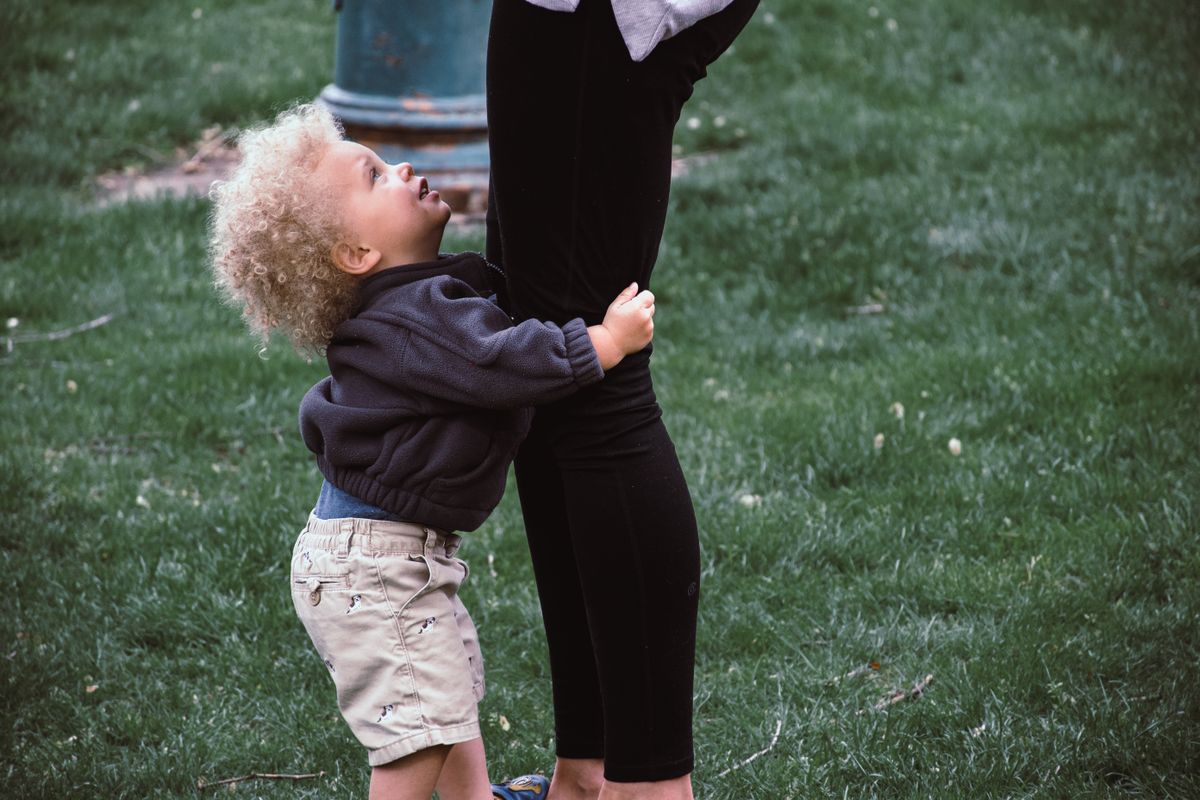 Young child clinging to a parent's legs, reluctant to separate